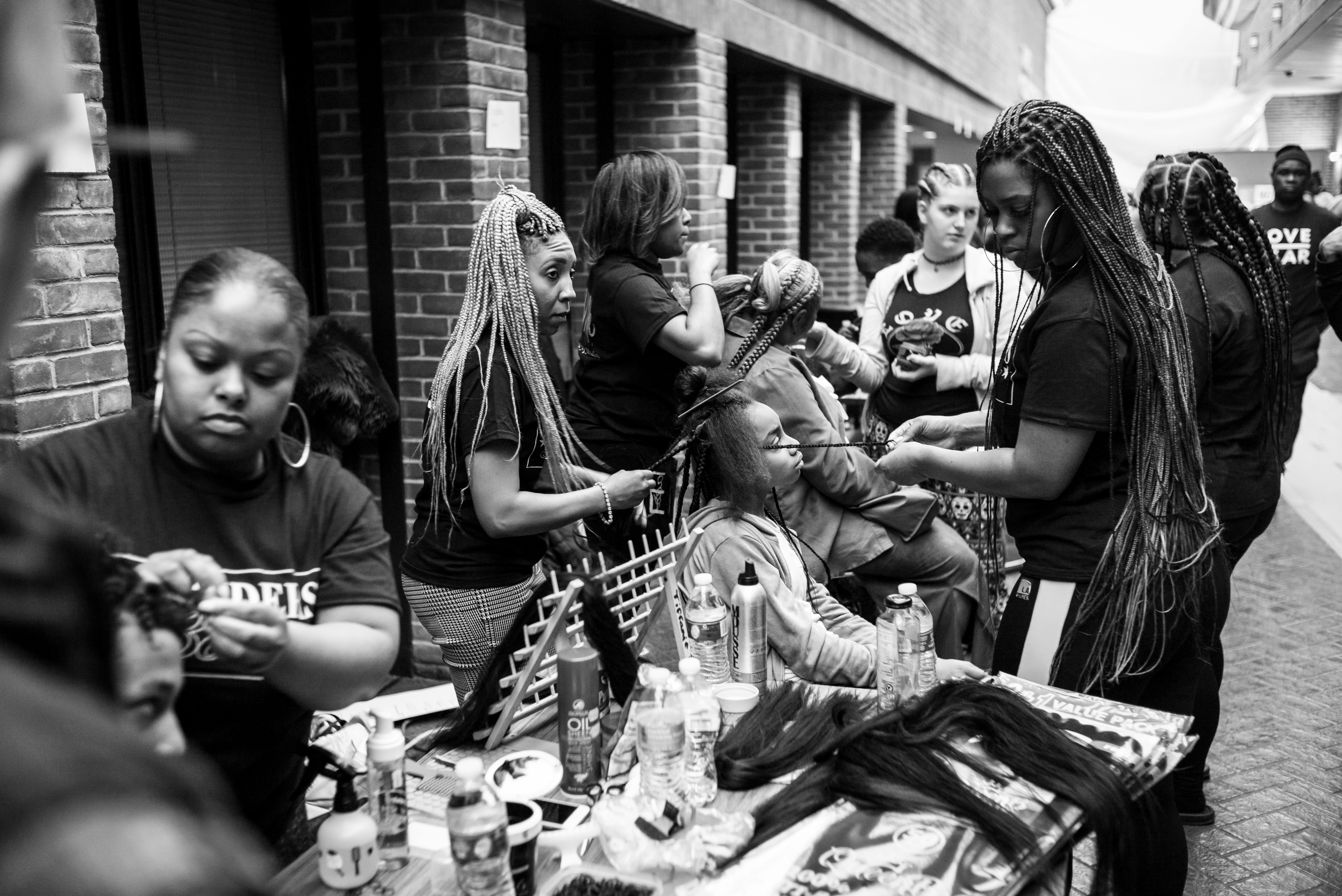 Braiders provide styling at the inaugural Healing City Baltimore two-day event. On the second day of the symposium braiders and barbers came together to celebrate their shops as healing spaces within communities in Baltimore. Photo by John Waire, thewairehouse.com; used with permission.