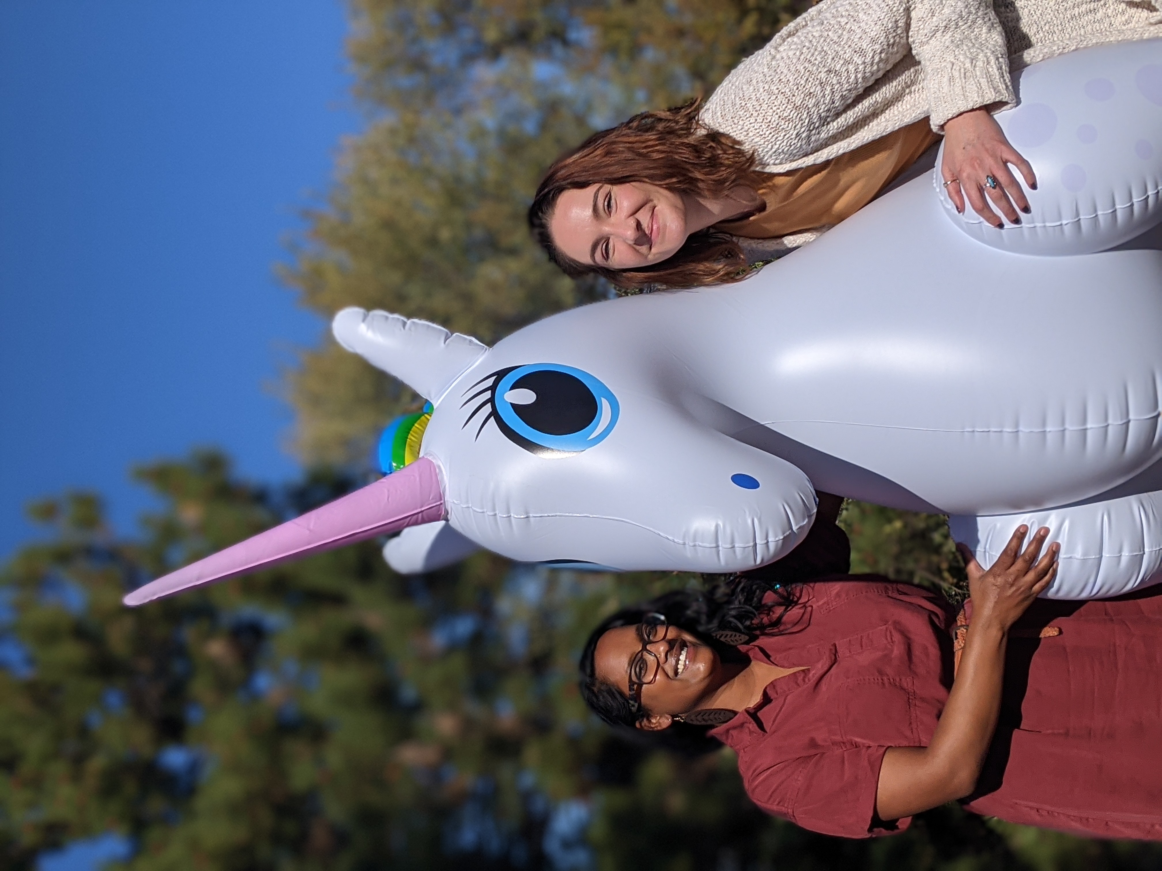 Two people standing with an inflatable unicorn. 